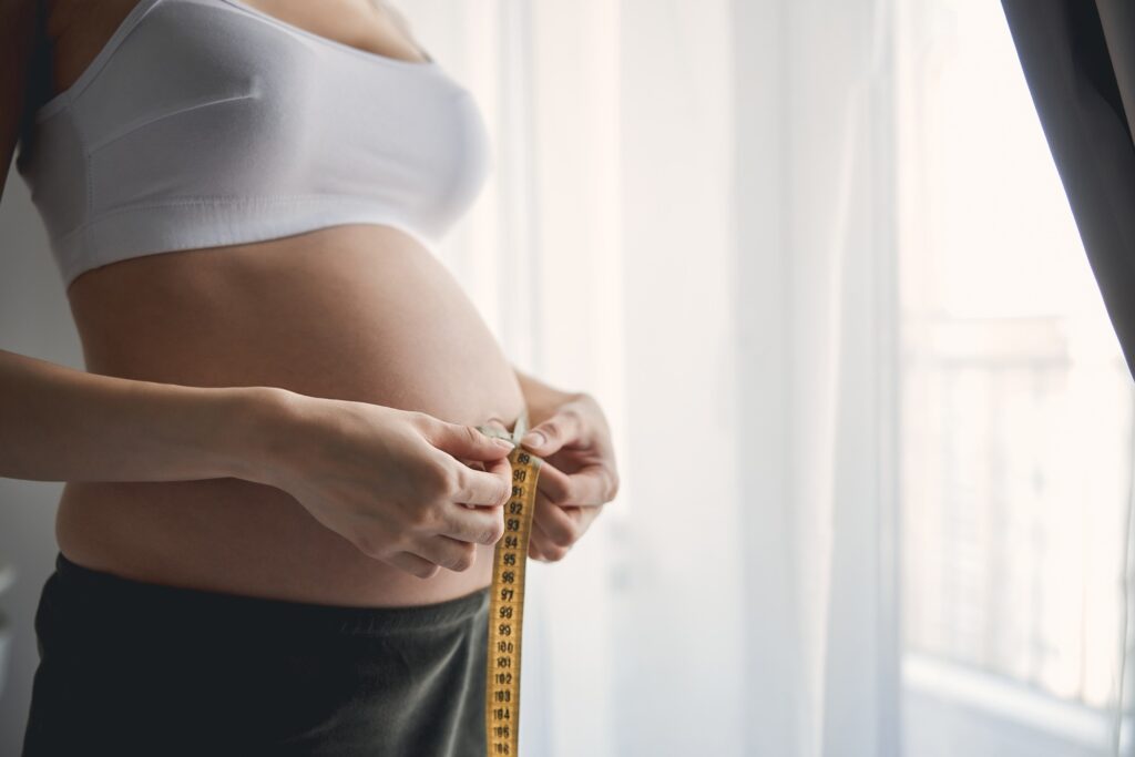 Tummy at the third trimester near the big window with yellow tape